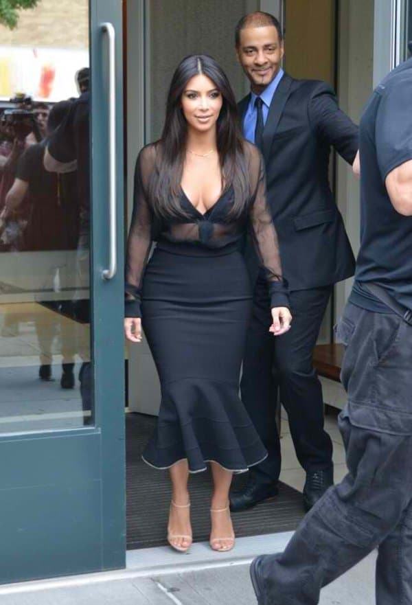 Kim Kardashian steps out in a stunning black pencil skirt with a flared hem and a sheer top, perfectly highlighting her hourglass figure at SiriusXM Radio station