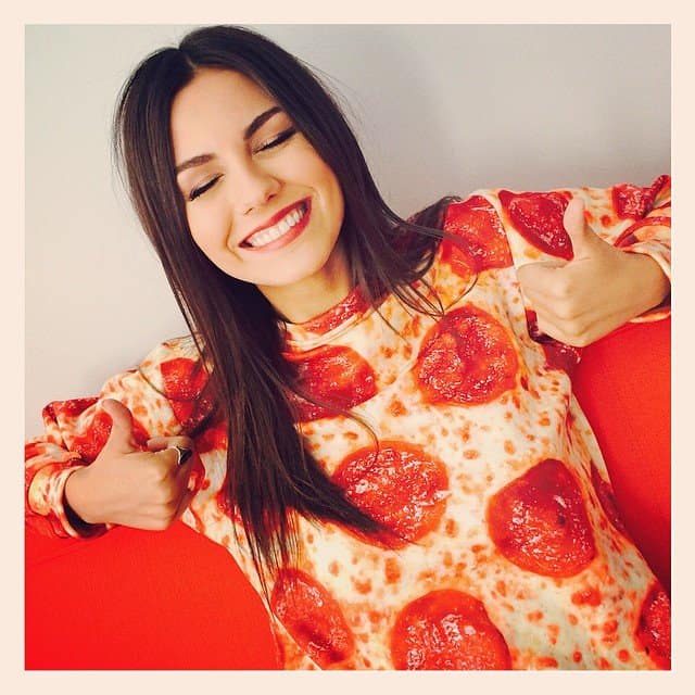 Victoria Justice gives a thumbs up while wearing a pepperoni pizza-print sweatshirt, embracing the fun and quirky fashion trend