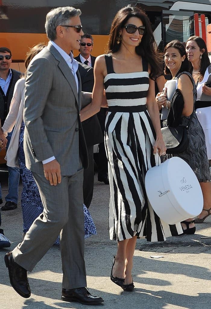 Amal Alamuddin stuns in a striped Dolce & Gabbana dress and black pumps, while George Clooney looks dapper in a grey suit as they arrive in Venice