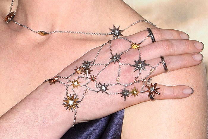Anne Hathaway's starry hand jewelry, adorned with delicate silver and gold stars, adds a celestial touch to her look at the Interstellar premiere