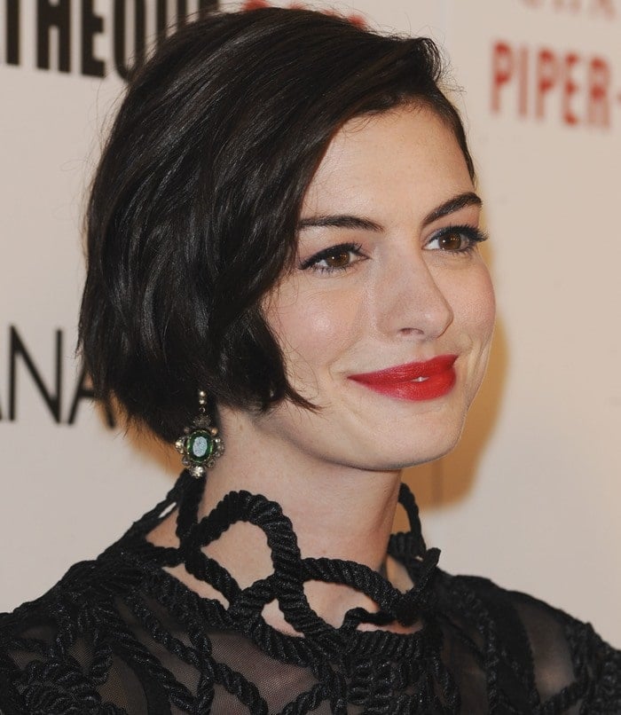 Anne Hathaway completes her look with a chic short bob hairstyle, styled in soft waves that frame her face, paired with bold red lips for a timeless pop of color and green statement earrings that add a touch of vintage glam at the 2014 American Cinematheque Award ceremony
