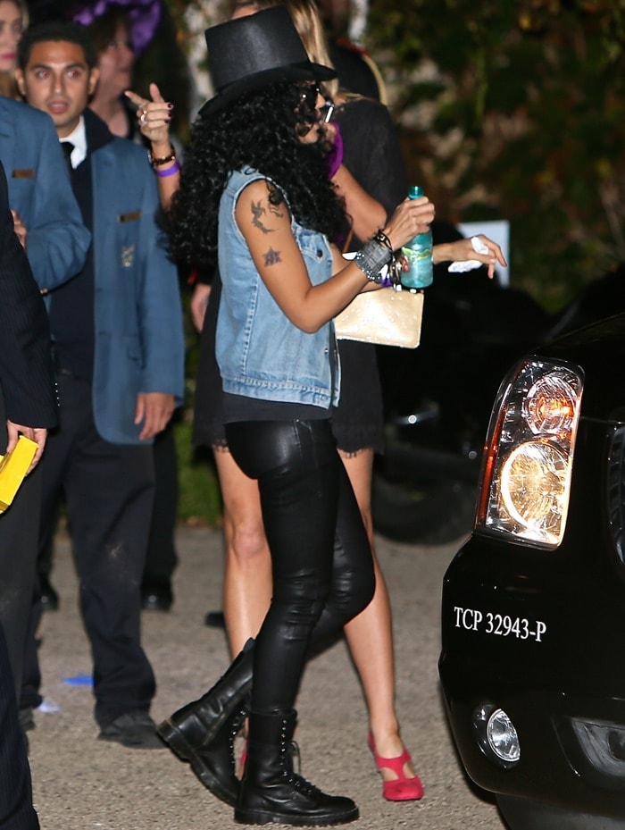 Jessica Alba embraced the Halloween spirit by adorning herself with dark sunglasses, a stylish black top hat, and a curly wig, perfectly channeling the legendary look of Slash