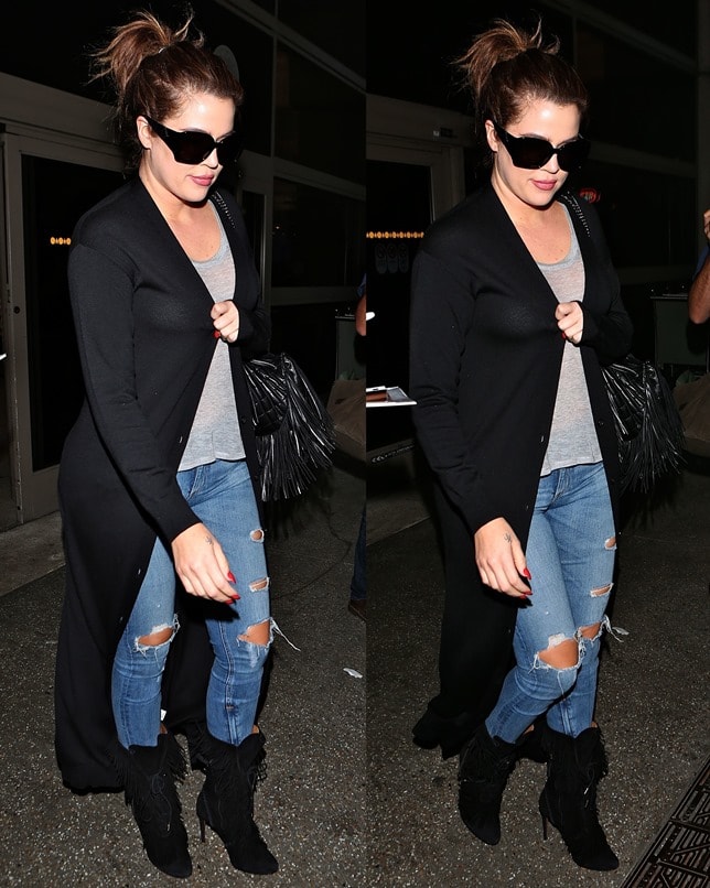 Khloe Kardashian flashed her bra in a see-through grey top, ripped denim jeans, black sunglasses, and a long black coat