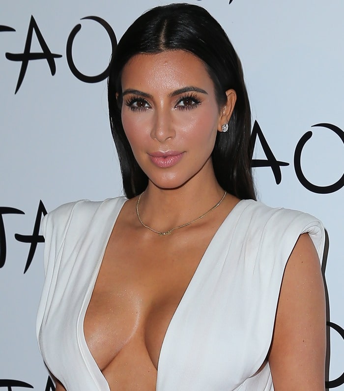 Kim Kardashian flashes side boob in a white wrap dress that barely covered her most infamous assets