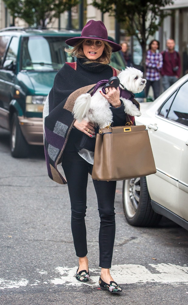 Olivia Palermo wears a Burberry color-block check blanket poncho with black pants, Alexander McQueen suede embroidered loafers, a Fendi leather Peek-a-Boo satchel bag, and a Janessa Leone Vera fedora