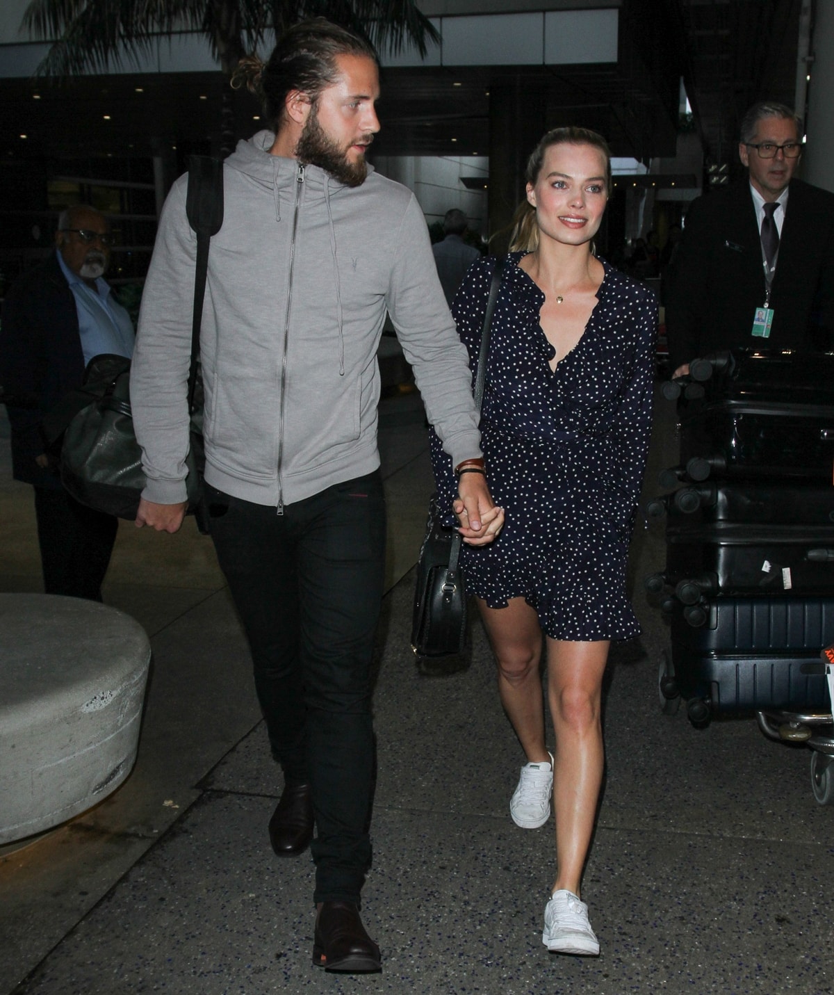 Margot Robbie steps out in a casual navy polka dot dress paired with white sneakers, holding hands with husband Tom Ackerley