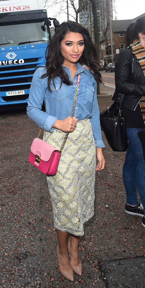 Vanessa White pairs a denim button-down with a lace-trimmed yellow pencil skirt, nude heels, and a pink crossbody bag, creating a chic and feminine street style look