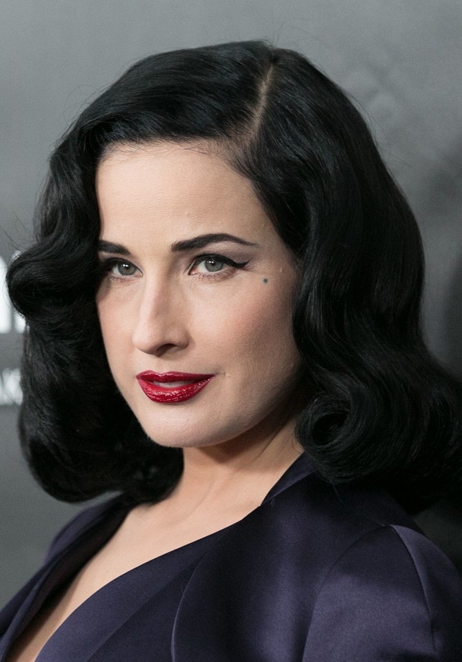 Dita Von Teese wearing her signature beauty look — pale skin, cat eyeliner, and red lipstick