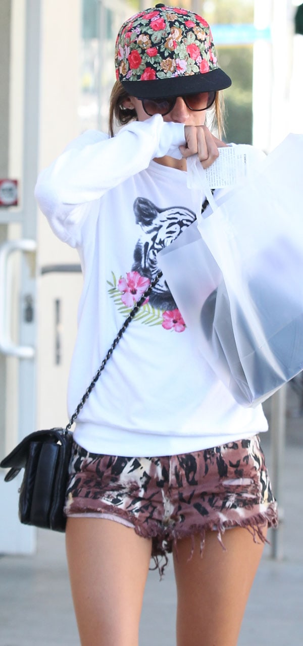 Alessandra Ambrosio adds a floral cap and oversized sunglasses for a feminine touch