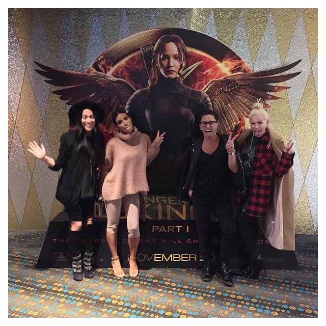 Kim Kardashian and friends pose in front of a "The Hunger Games: Mockingjay – Part 1" poster at a private theater in Australia