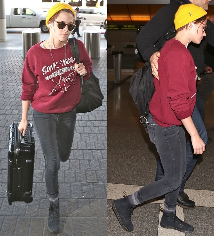 Kristen Stewart wearing faded skinny jeans, a wine red Sonic Youth sweatshirt, a bright yellow beanie, black Raybans, and black boots