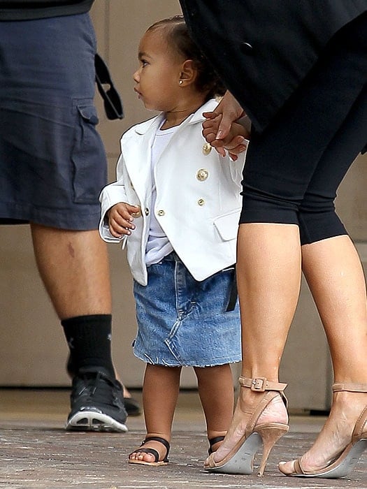 Seventeen-month-old North West sporting her custom Balmain blazer and holding on to mom Kim's hand