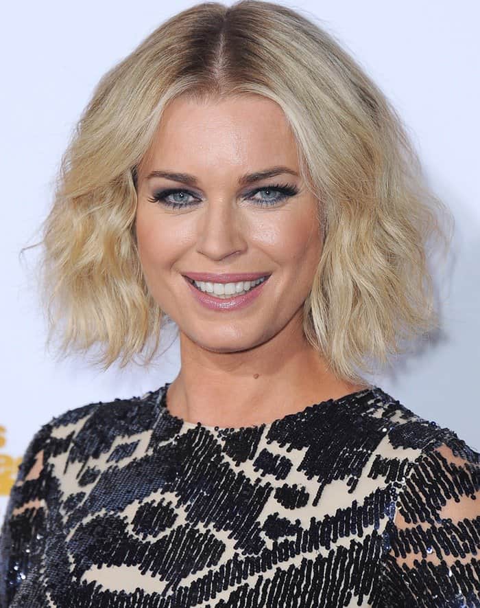 Rebecca Romijn looks radiant with her tousled blonde waves, smoky eye makeup, and bright, confident smile