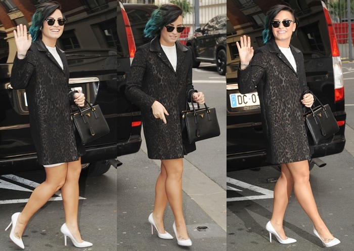 Demi Lovato wearing a Sandro leopard-print jacquard coat over a white dress