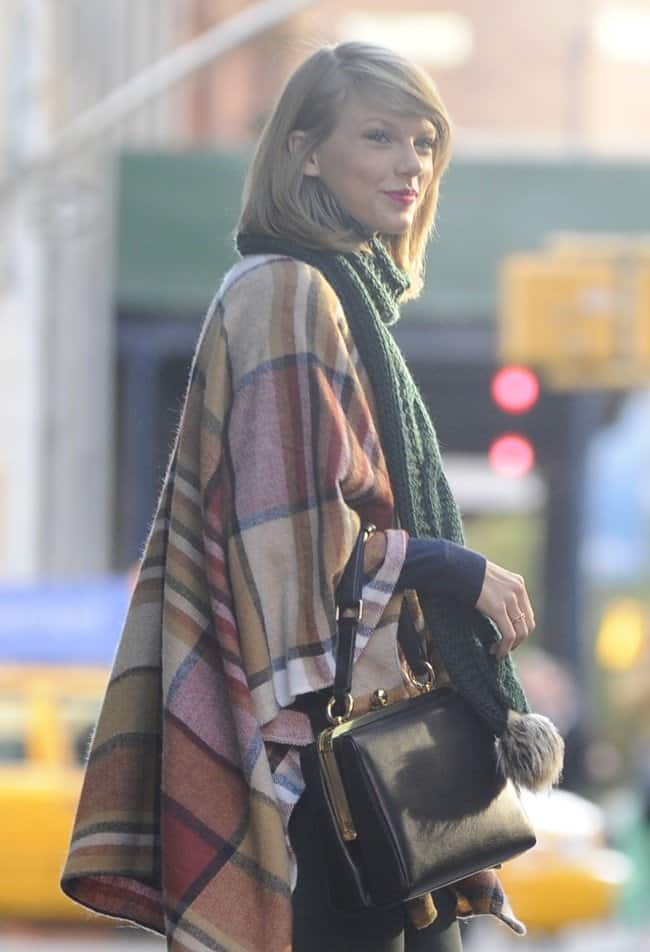 Braving the chilly New York City weather, Taylor Swift expertly layers a warm knitted scarf over a cozy checkered cape for a stylish and functional winter look