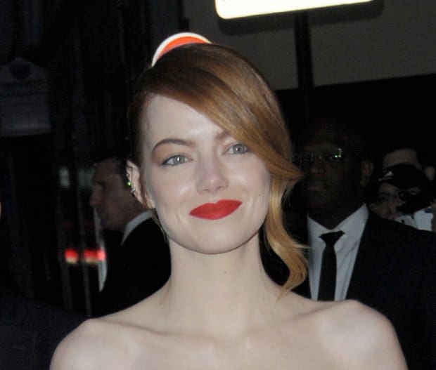 Emma Stone's flawless look is highlighted by her sleek side-swept hairstyle and vibrant red lipstick