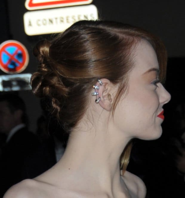 Emma Stone's elegant look is enhanced by her delicate, multi-stud ear cuff, adding a touch of edgy sophistication to her polished updo and bold red lip