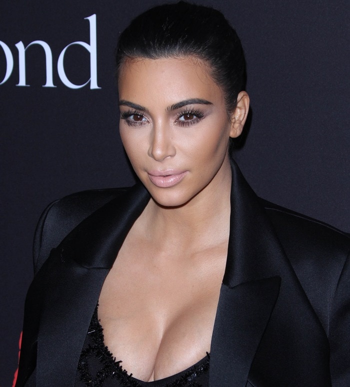 Kim Kardashian wearing a black bodysuit worn under a see-through fishnet dress