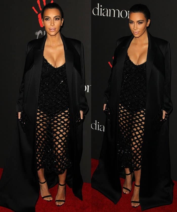 Kim Kardashian wears a black bodysuit with a fishnet overlay dress and a floor-length satin coat at Rihanna's Diamond Ball
