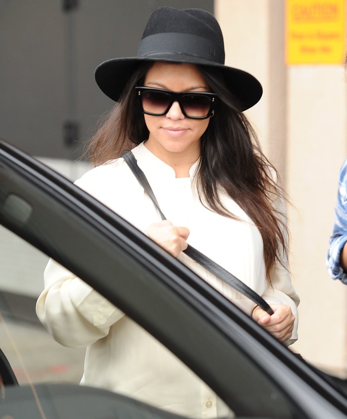 Kourtney Kardashian rocks a black hat with a cream tunic shirt