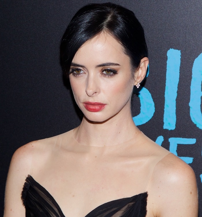 Krysten Ritter accentuates her striking eyes with bold eyeliner and a soft red lip, complemented by delicate diamond stud earrings at the premiere of Big Eyes