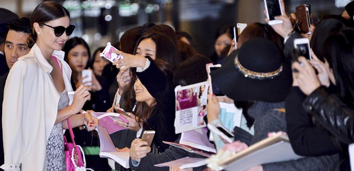 Miranda Kerr in a white coat and white geometric-pattern dress at Narita International Airport in Narita, Japan, on December 9, 2014