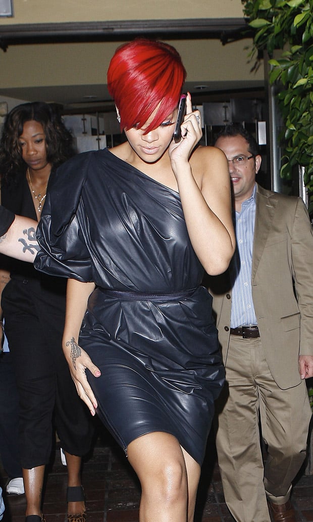Rihanna steps out in a Lanvin one-shoulder dress, accessorized minimally, highlighting her bold red hair and understated makeup, while chatting on the phone