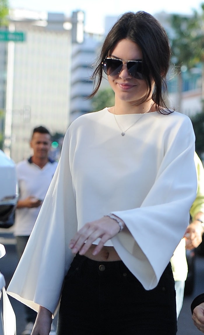 Kendall Jenner wears an elegant white crop top with black skinny jeans