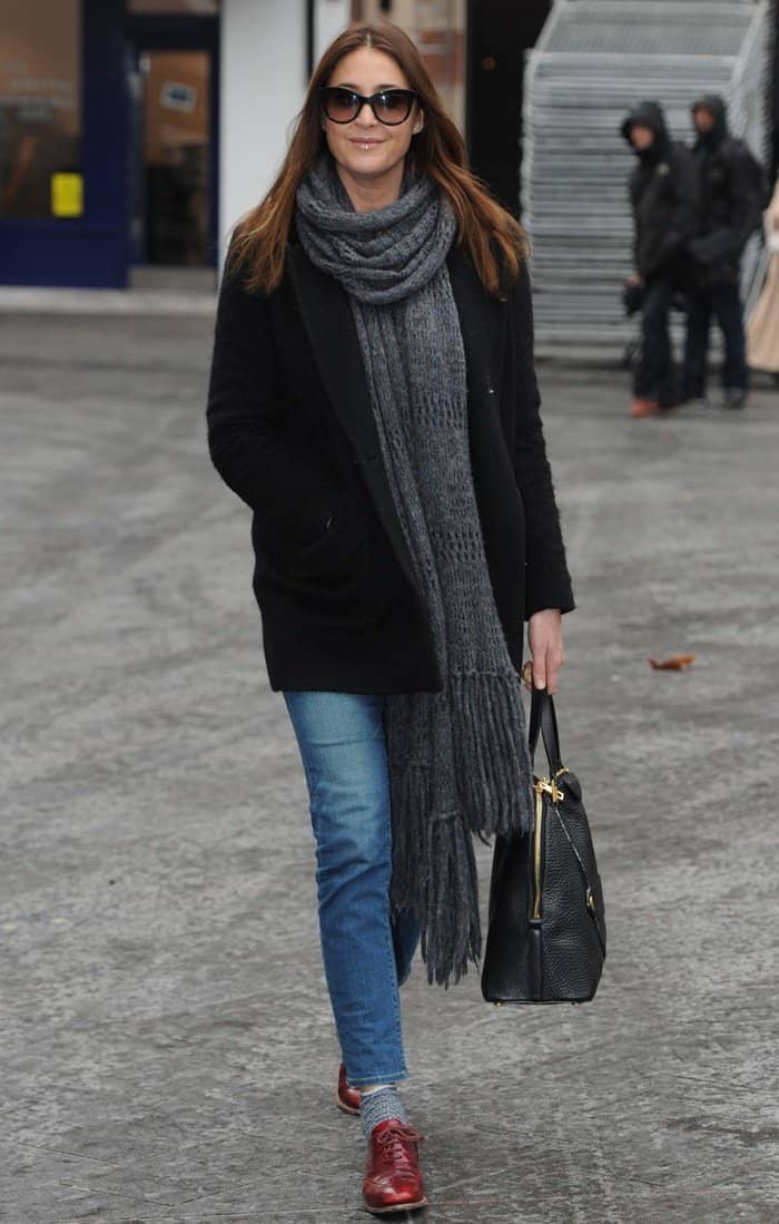 Lisa Snowdon pairs her fringed scarf with a black coat, blue jeans, and red brogues for a chic and effortless street style look