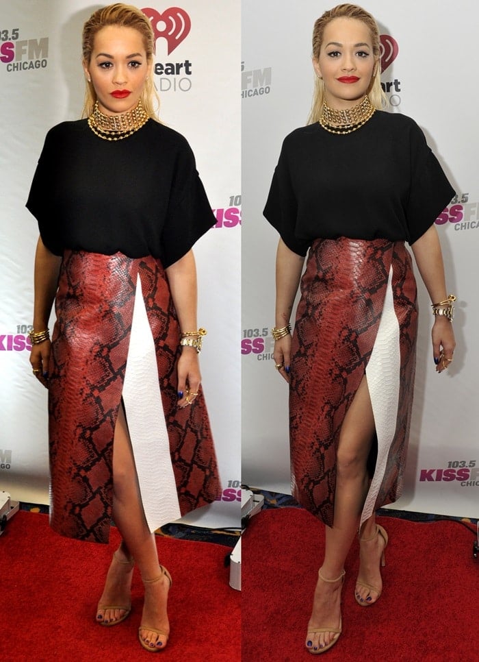 Rita Ora flaunts her legs in a black draped top and a red python skirt with a thigh-high slit