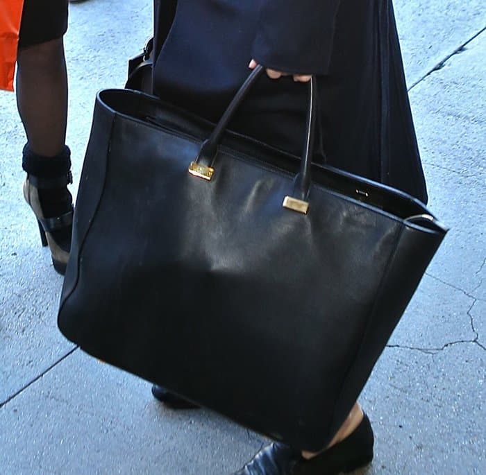 Ashley Olsen carries The Row's oversized black leather tote, a minimalist luxury piece that perfectly complements her sleek travel ensemble