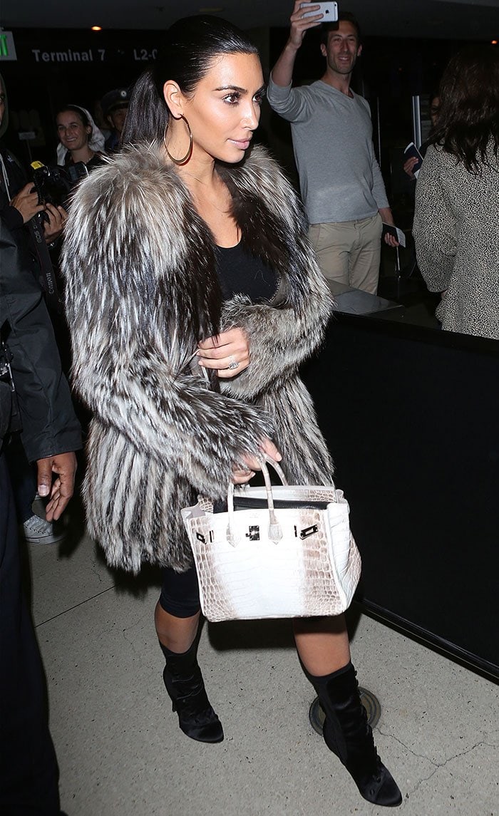 Kim Kardashian in knee-length leggings, a sheer long-sleeved top, and a luxurious designer fur coat