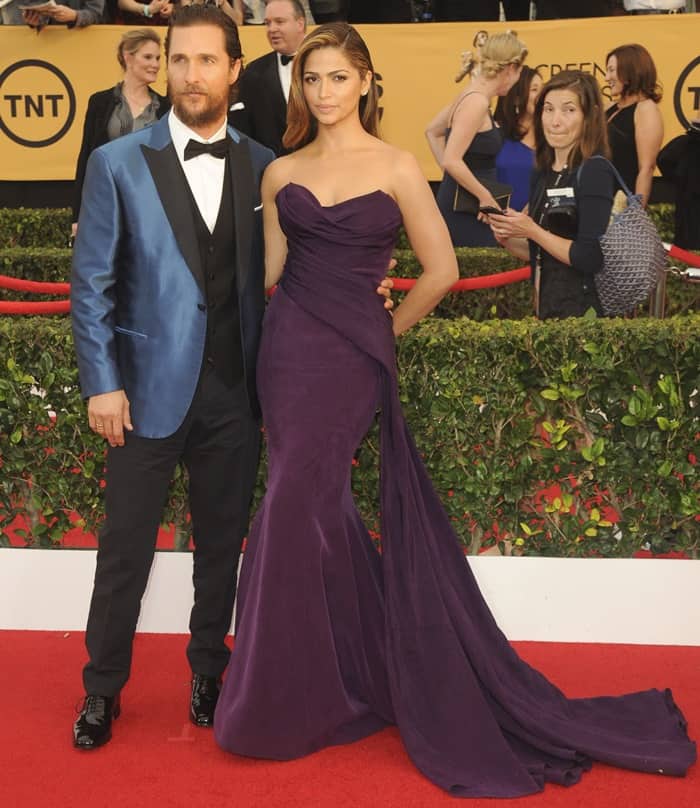 Camila Alves stuns in a draped aubergine Donna Karan gown with a side train, accompanied by Matthew McConaughey in a striking blue tuxedo on the red carpet at the 2015 SAG Awards