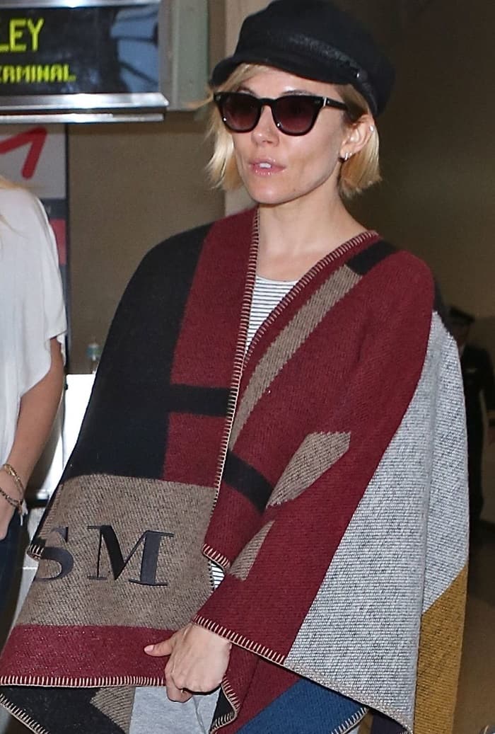 Sienna Miller at LAX in an all-gray attire topped with a Burberry blanket wrap