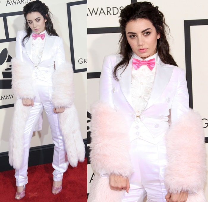 Charli XCX brought quirky glamour to the red carpet in a white Moschino tuxedo with satin lapels, a hot pink bow tie, and oversized pink fur cuffs, finishing the look with sparkling mules that screamed playful extravagance