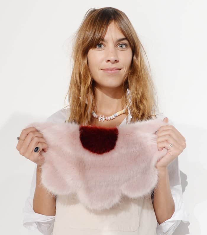 Alexa Chung embraces playful elegance as she showcases her pink Shrimps Daisy clutch, a whimsical furry statement piece with scalloped edges and a bold accent