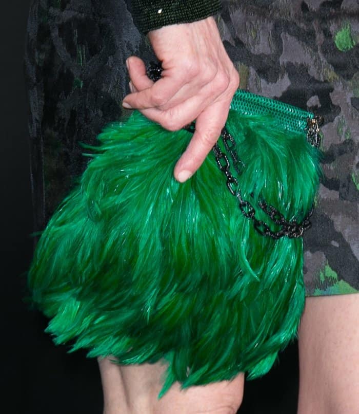 Julianne Moore elevates her look with a bold emerald green feather clutch, adding a touch of glamour and texture to her sophisticated ensemble