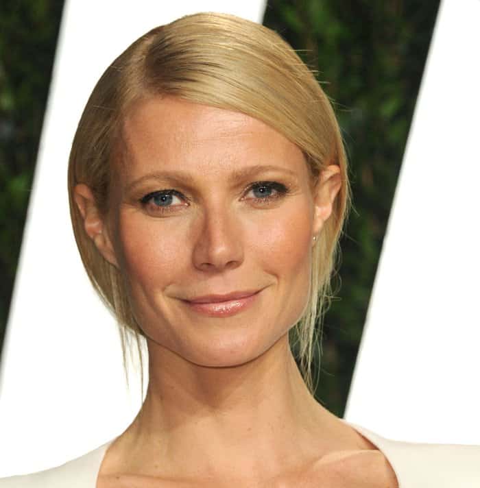 Gwyneth Paltrow styled her white cape dress with sleek, side-parted hair and minimal makeup, highlighting her natural beauty at the Oscars