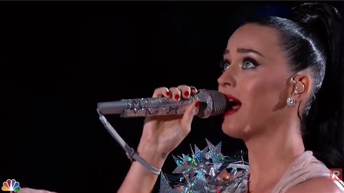 Katy Perry holding a silver-star-covered mic while singing "Firework"