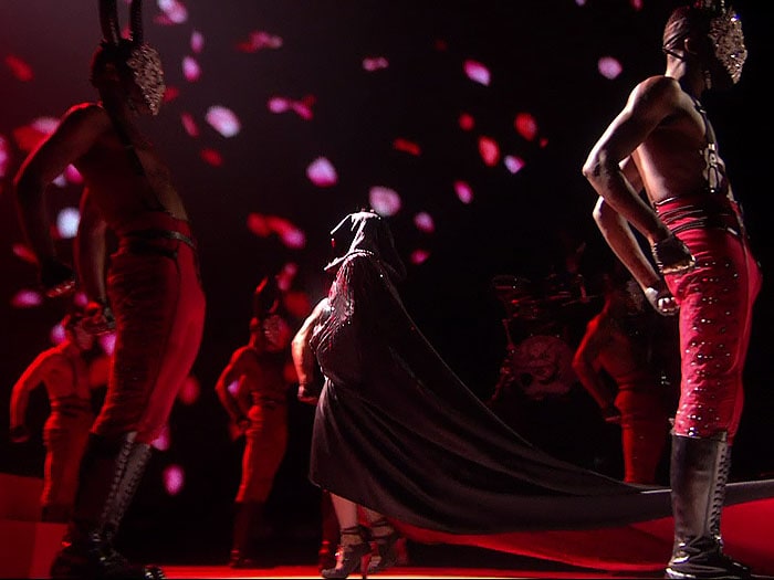 Madonna walking towards the stairs and wearing the Armani Privè cape that caused her infamous fall