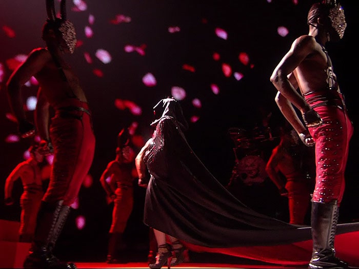 Madonna walking towards the stairs and wearing the Armani Privé cape that caused her infamous fall