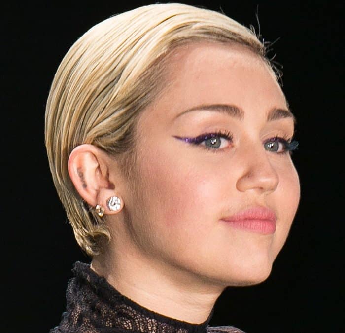 Miley Cyrus showcases her 'LOVE' tattoo inked on the antihelix of her right ear at the Tom Ford Autumn/Winter 2015 presentation