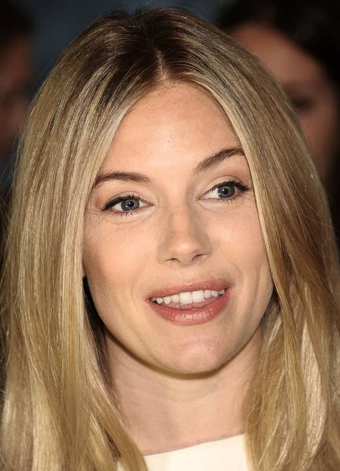 Sienna Miller styled her white cape dress with loose, center-parted hair and natural makeup