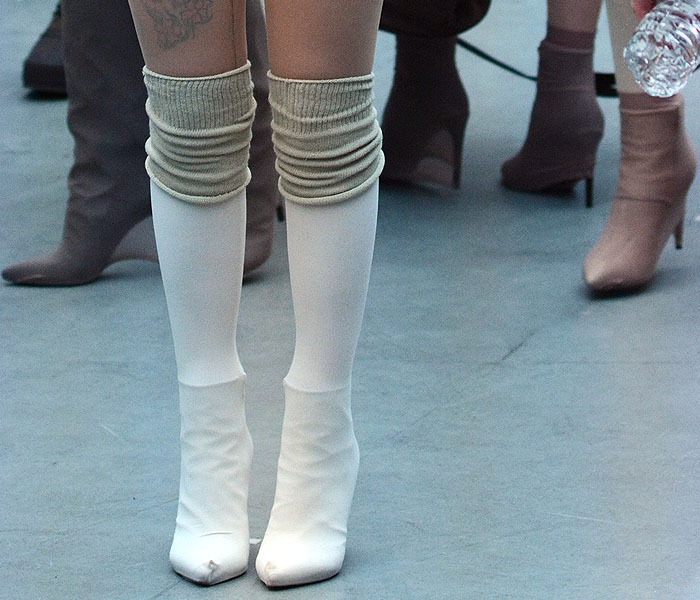 Models wearing ankle boots and tall boots covered in socks and pantyhose at the Yeezy fashion show