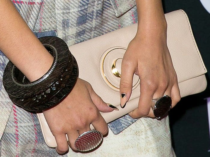 Closeup of Zendaya's accessories including dark brown John Hardy wooden bracelets, silver disc rings, and a nude Orton "Deco" clutch