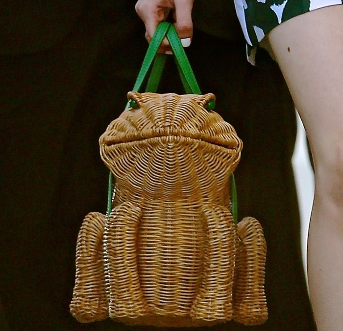 Maisie Williams totes a charming frog-shaped Kate Spade New York handbag in glossy wicker