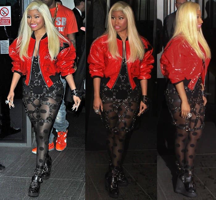Nicki Minaj goes bold in a red PVC bomber jacket paired with a daring bondage-style mesh dress, buckled boots, and her signature fearless attitude