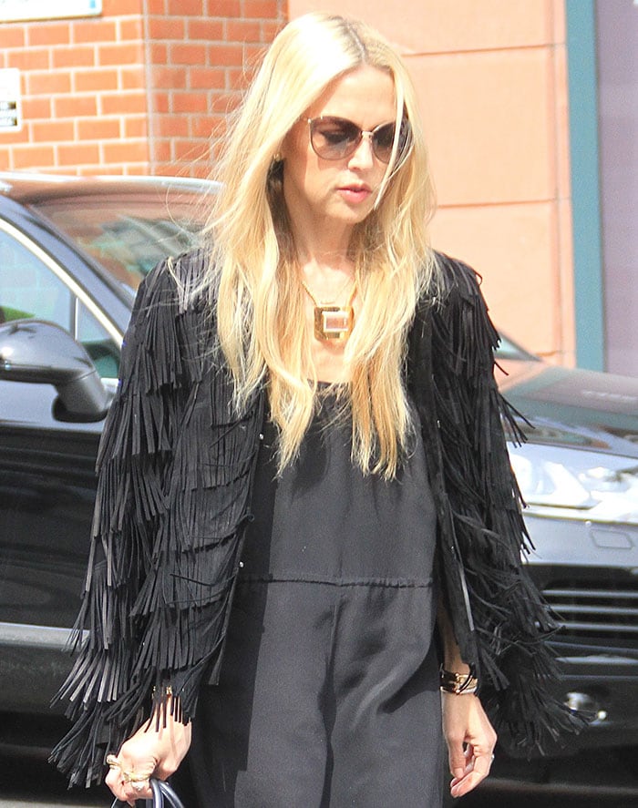 Rachel Zoe draping a black fringed jacket over her shoulders