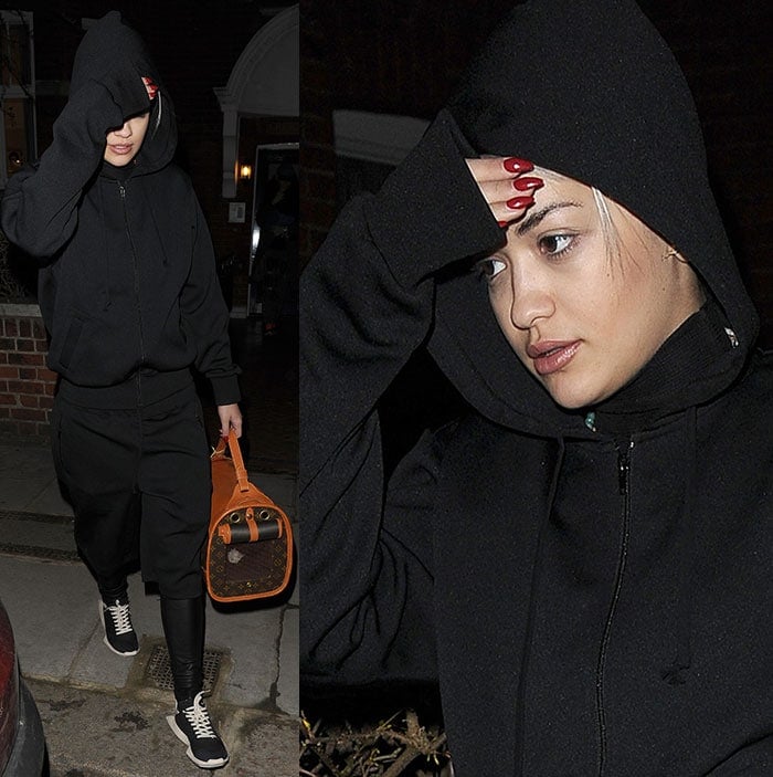 Rita Ora wears a black tracksuit with a hoodie and knee-length shorts