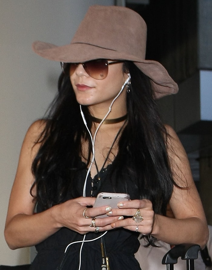 Actress Vanessa Hudgens tries to go incognito as she wears a wide-brimmed hat and aviator sunglasses at Los Angeles International Airport (LAX) while listening with her earphones on February 25, 2015